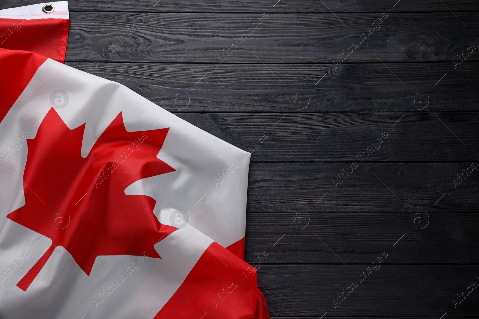 Photo of Flag of Canada on dark wooden table, top view. Space for text