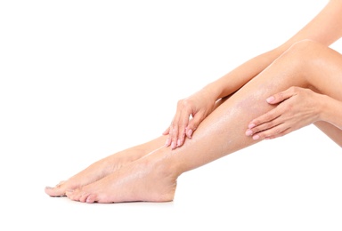 Photo of Young woman applying body scrub on leg against white background