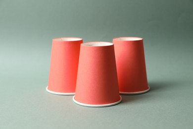 Three red cups on pale olive background. Thimblerig game