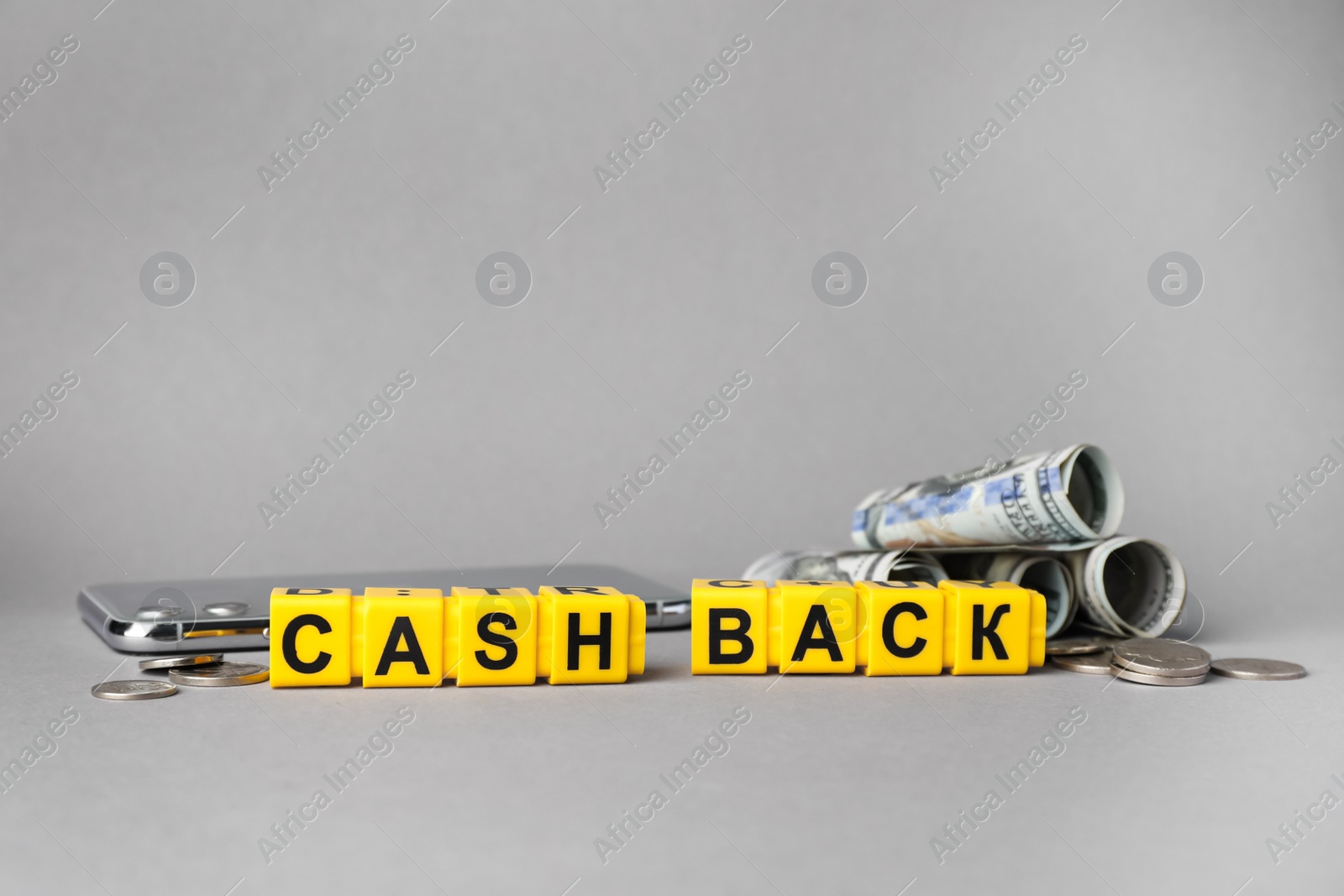 Photo of Word Cashback made with cubes, money and smartphone on grey background