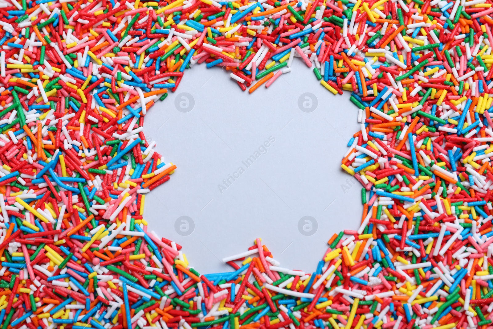 Photo of Frame of colorful sprinkles on light grey background, flat lay with space for text. Confectionery decor