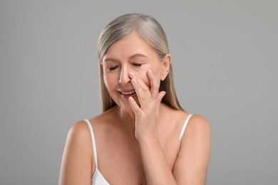 Photo of Beautiful mature woman with healthy skin on gray background