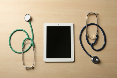 Photo of Flat lay composition with stethoscopes and tablet on table, space for text. Medical students stuff