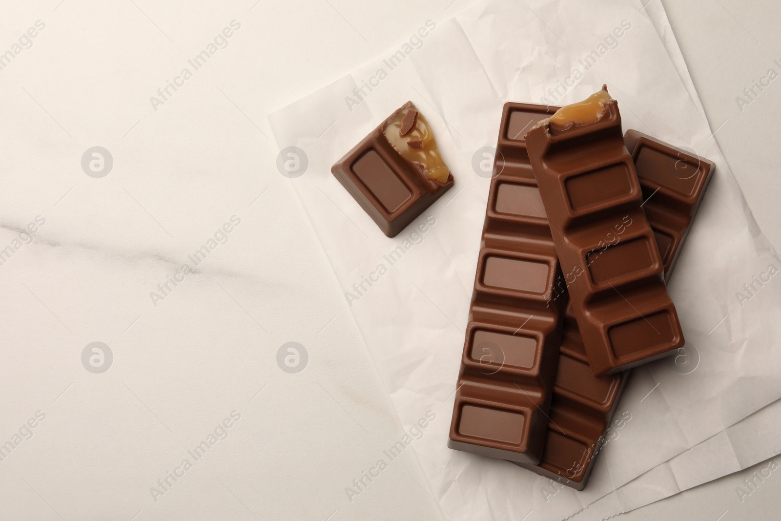 Photo of Tasty chocolate bars on white table, top view. Space for text