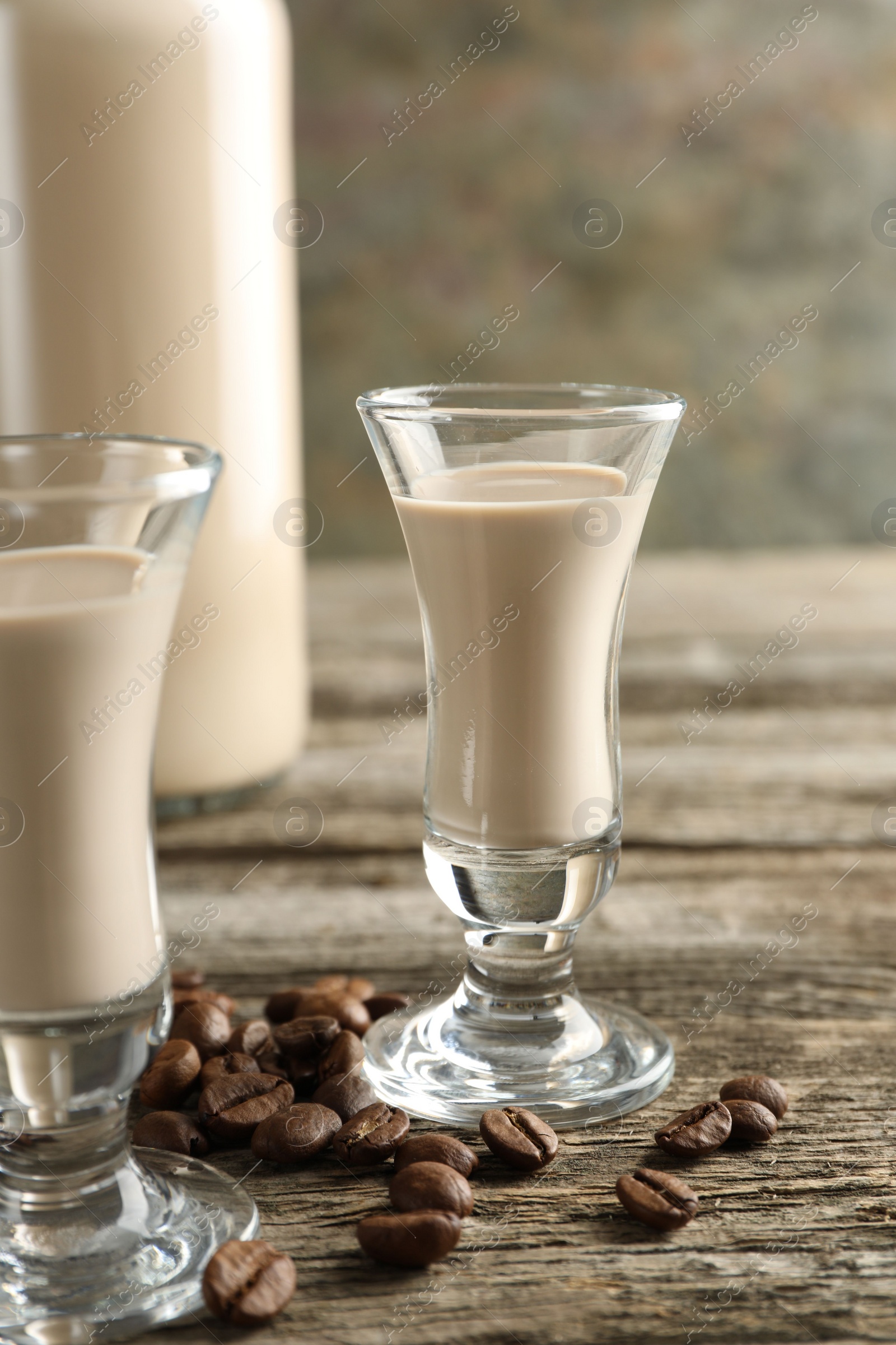 Photo of Coffee cream liqueur in glasses and beans on wooden table