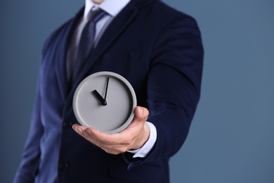 Photo of Businessman holding alarm clock on color background. Time concept