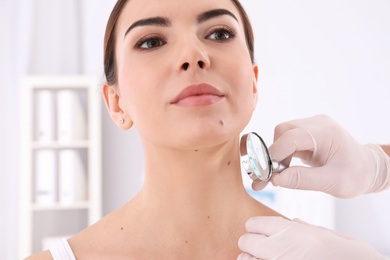 Dermatologist examining patient with magnifying glass in clinic