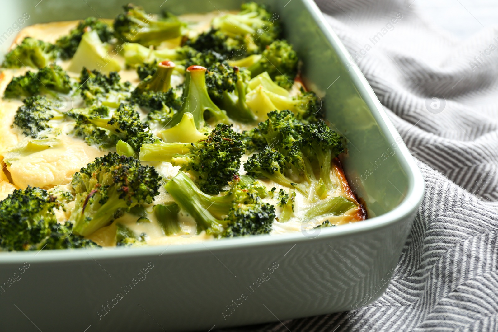 Photo of Tasty broccoli casserole in baking dish on table, closeup