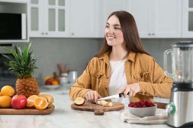 Photo of Woman preparing ingredients for tasty smoothie at white marble table in kitchen