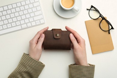 Photo of Woman holding leather card holder at white table, top view