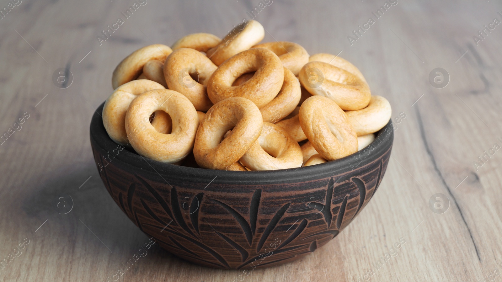 Photo of Bowl of tasty dry bagels (sushki) on wooden table