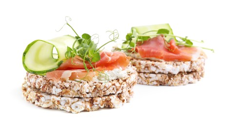 Photo of Crunchy buckwheat cakes with cream cheese, prosciutto and cucumber slices on white background