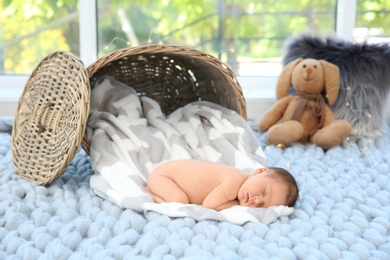 Adorable newborn baby sleeping on soft plaid near wicker basket