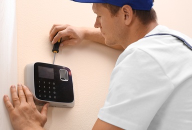 Photo of Male technician installing security alarm system indoors