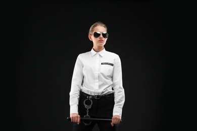 Photo of Female security guard with police baton on dark background