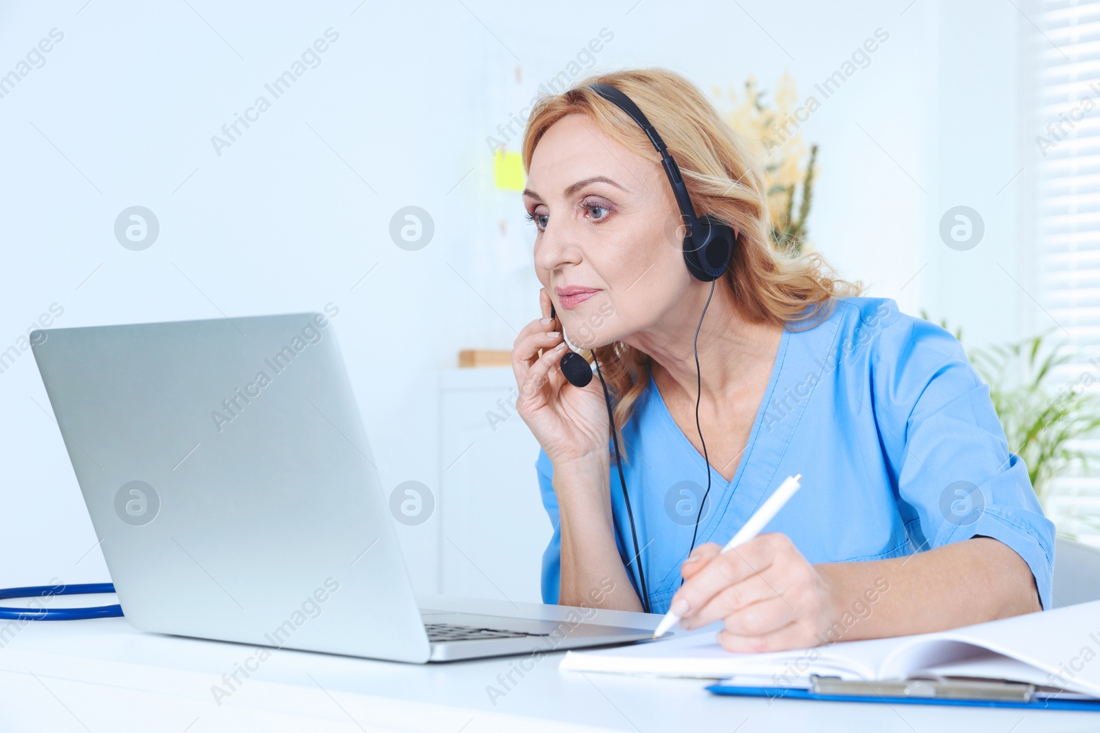 Photo of Doctor with laptop and headphones consulting patient in clinic. Online medicine concept