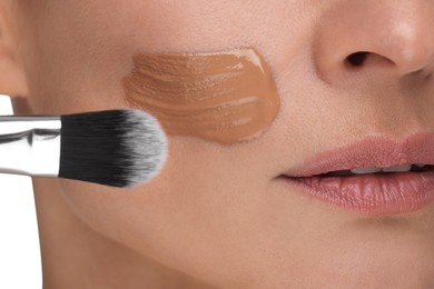 Photo of Woman applying foundation on face with brush, closeup