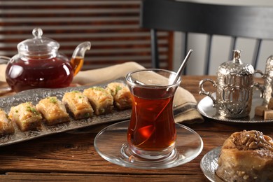 Photo of Turkish tea and sweets served in vintage tea set on wooden table