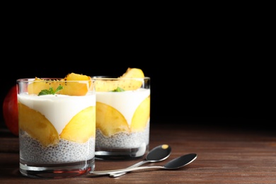 Photo of Tasty peach dessert with yogurt and chia seeds served on wooden table. Space for text
