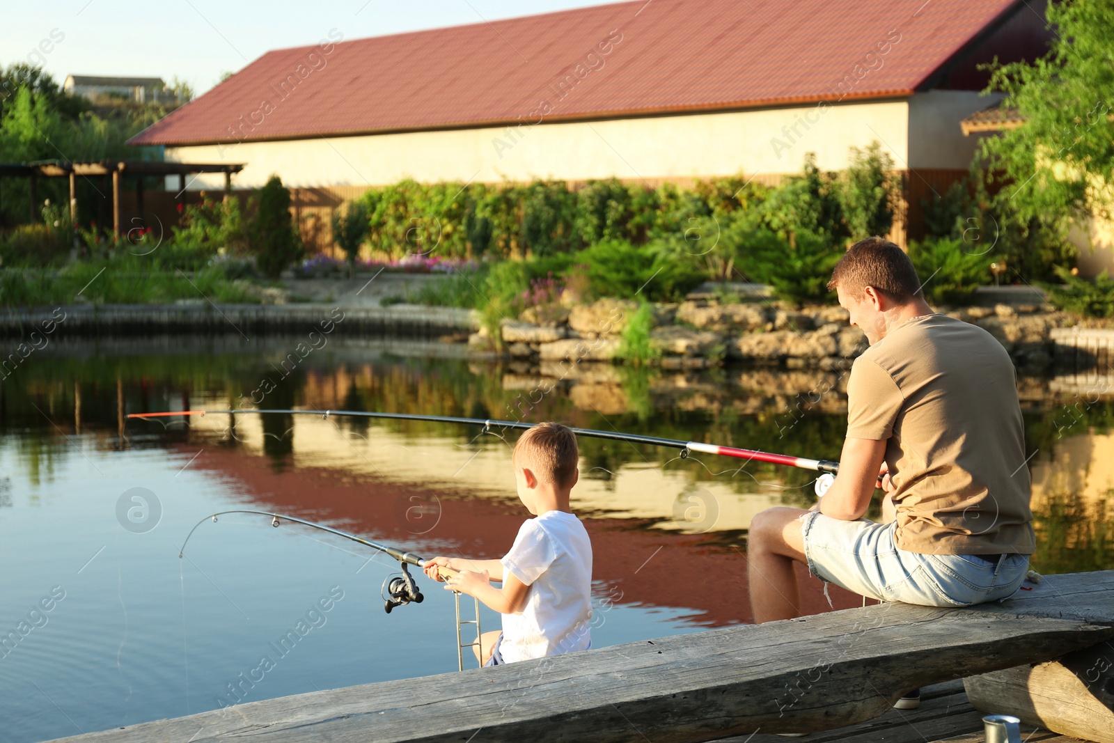 Photo of Dad and son fishing together on sunny day