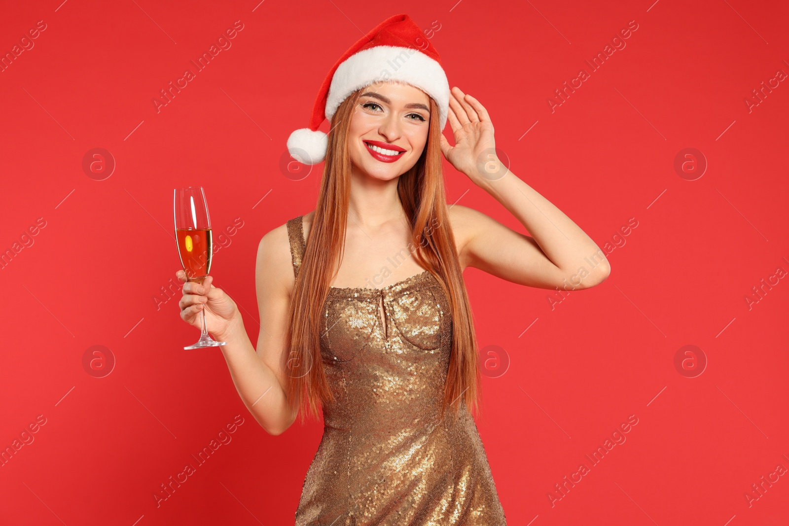 Photo of Young woman in Santa hat with glass of wine on red background. Christmas celebration