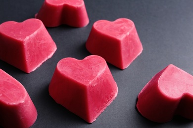 Photo of Heart shaped berry ice cubes on black background