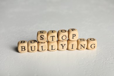Phrase Stop Bullying made of wooden cubes with letters on stone surface, closeup