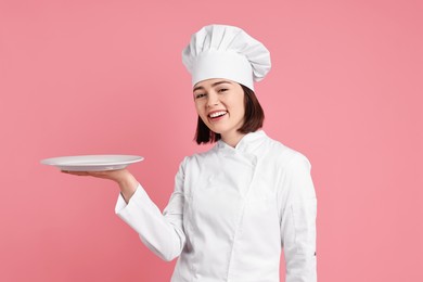 Happy confectioner with plate on pink background