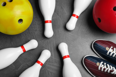 Photo of Bowling shoes, pins and balls on grey stone table, flat lay