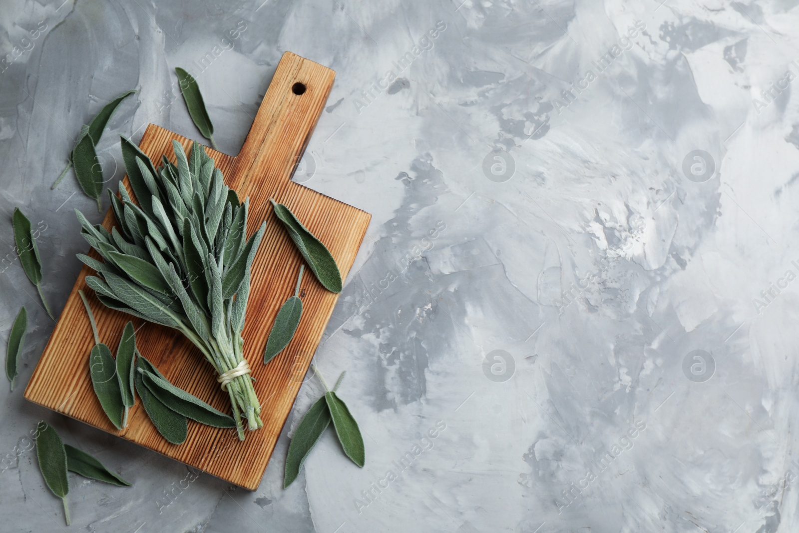 Photo of Wooden board with fresh green sage on grey table, flat lay. Space for text