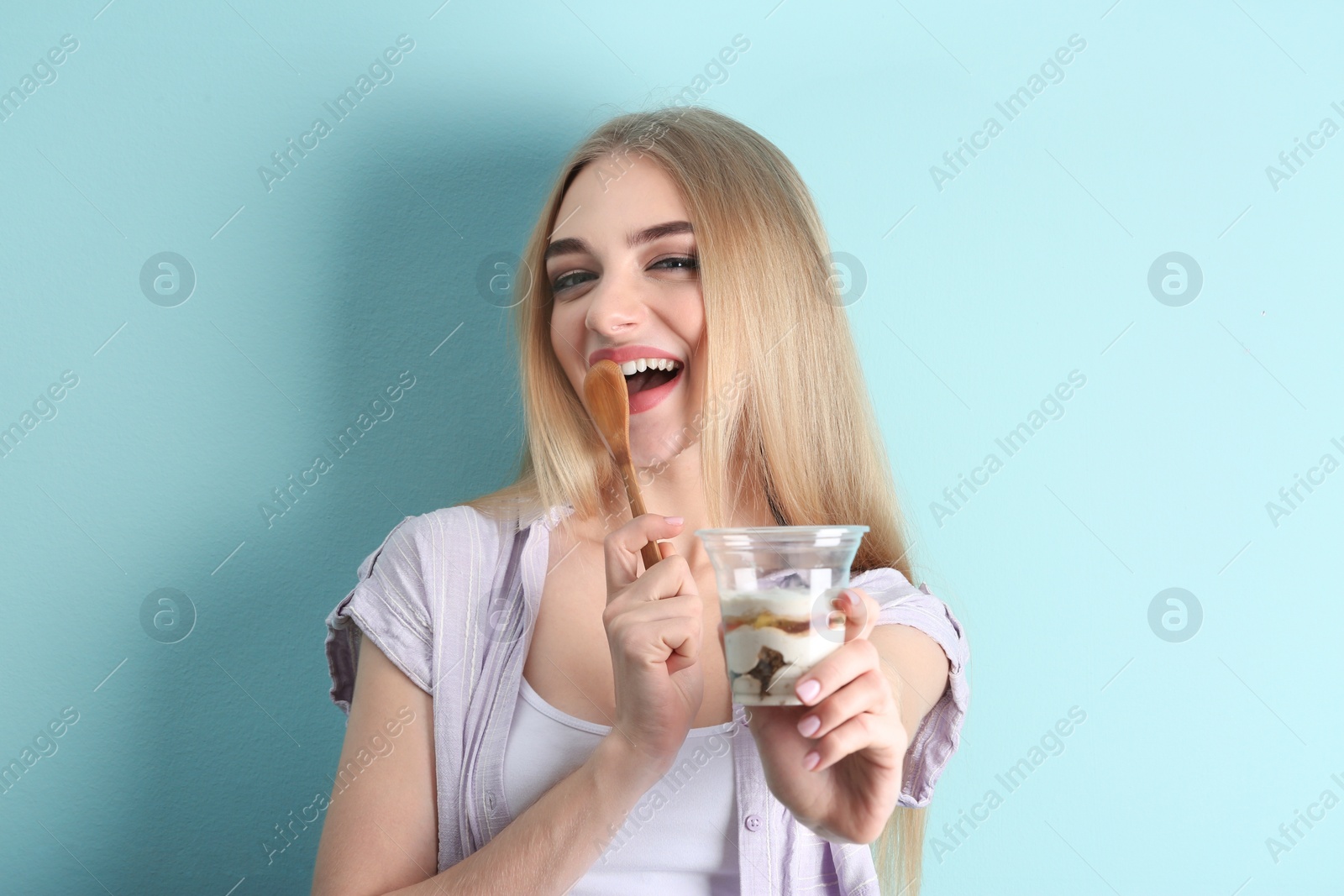 Photo of Young woman with yogurt on color background