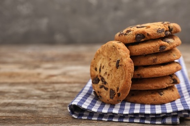 Photo of Stack of cookies with chocolate chips on wooden table, space for text