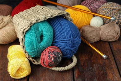Photo of Soft woolen yarns and knitting needles on wooden table