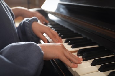 Photo of Little child playing piano, closeup. Music lesson