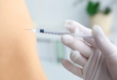 Photo of Doctor vaccinating male patient in clinic, closeup