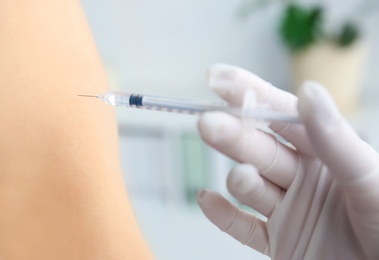 Doctor vaccinating male patient in clinic, closeup