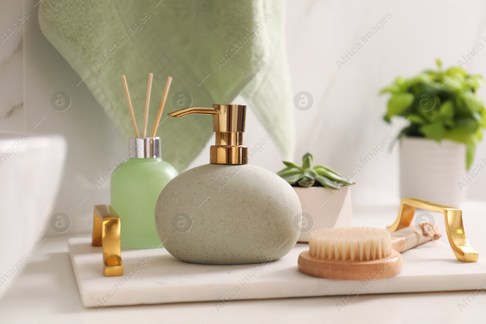 Photo of Tray with toiletries, air reed freshener and plant on countertop in bathroom