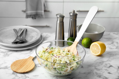 Bowl with fresh cabbage salad on marble table in kitchen