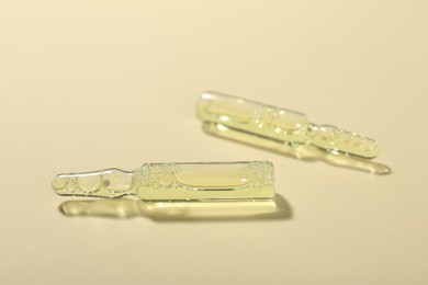 Photo of Glass ampoules with liquid on beige background