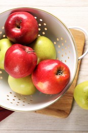 Photo of Fresh apples in colander on white wooden table, flat lay