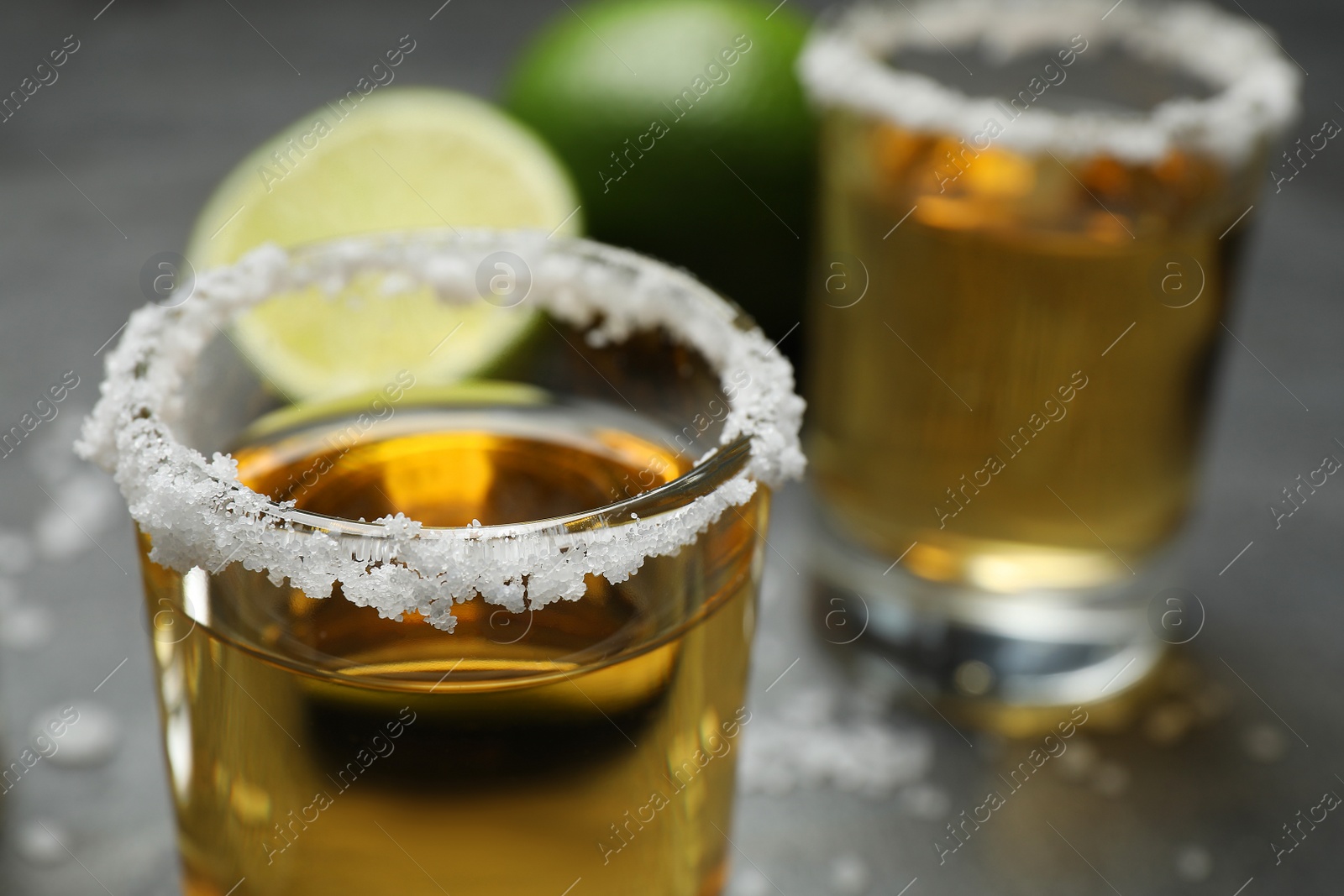 Photo of Mexican Tequila shots, with salt on grey table, closeup