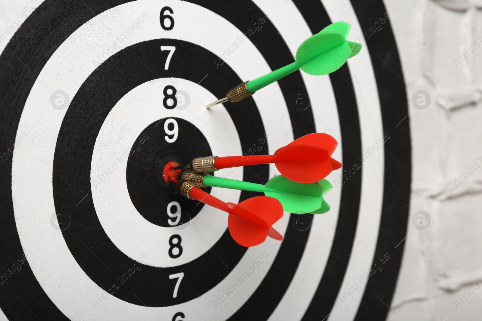 Photo of Arrows hitting dart board on white textured wall, closeup