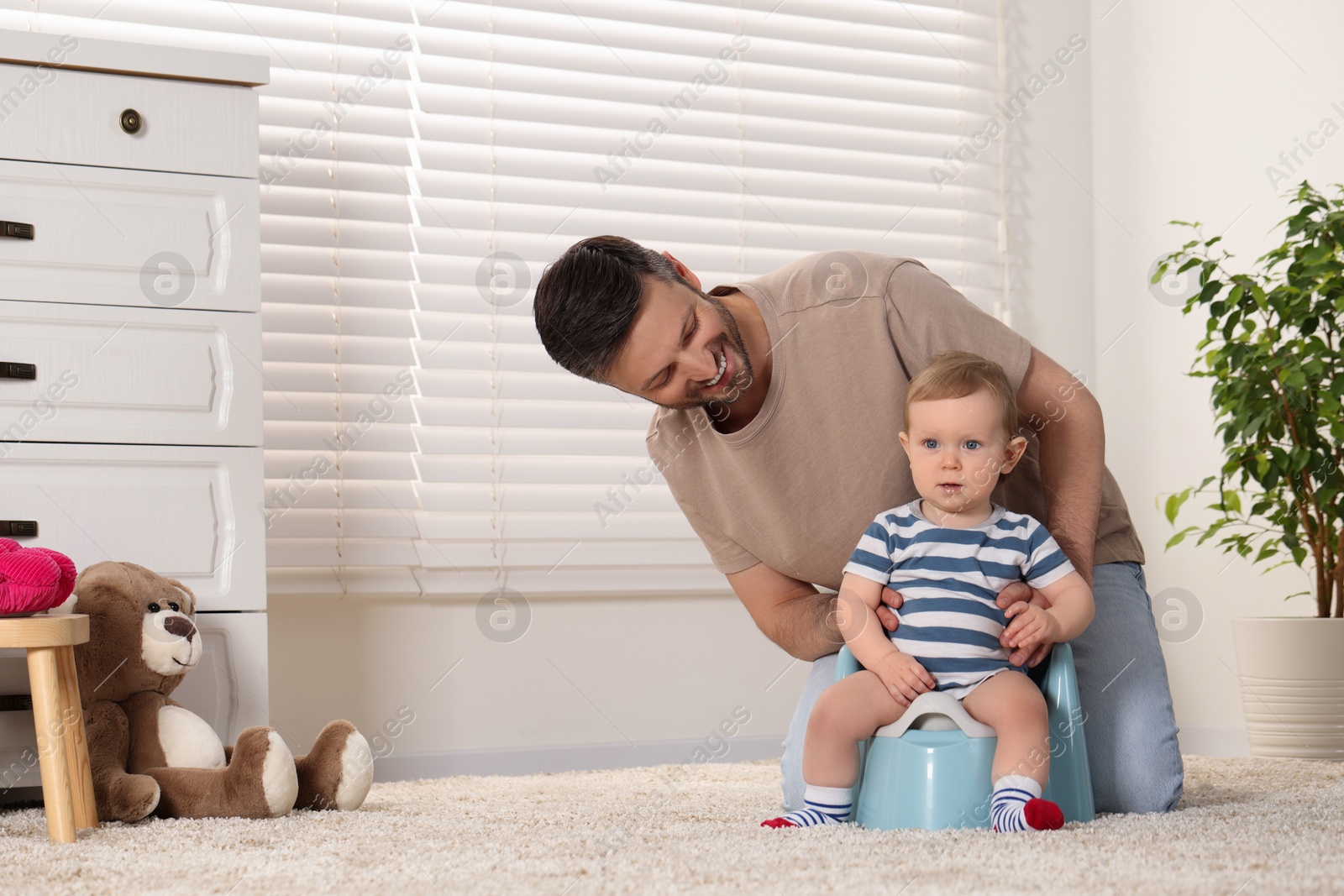 Photo of Father training his child to sit on baby potty indoors. Space for text