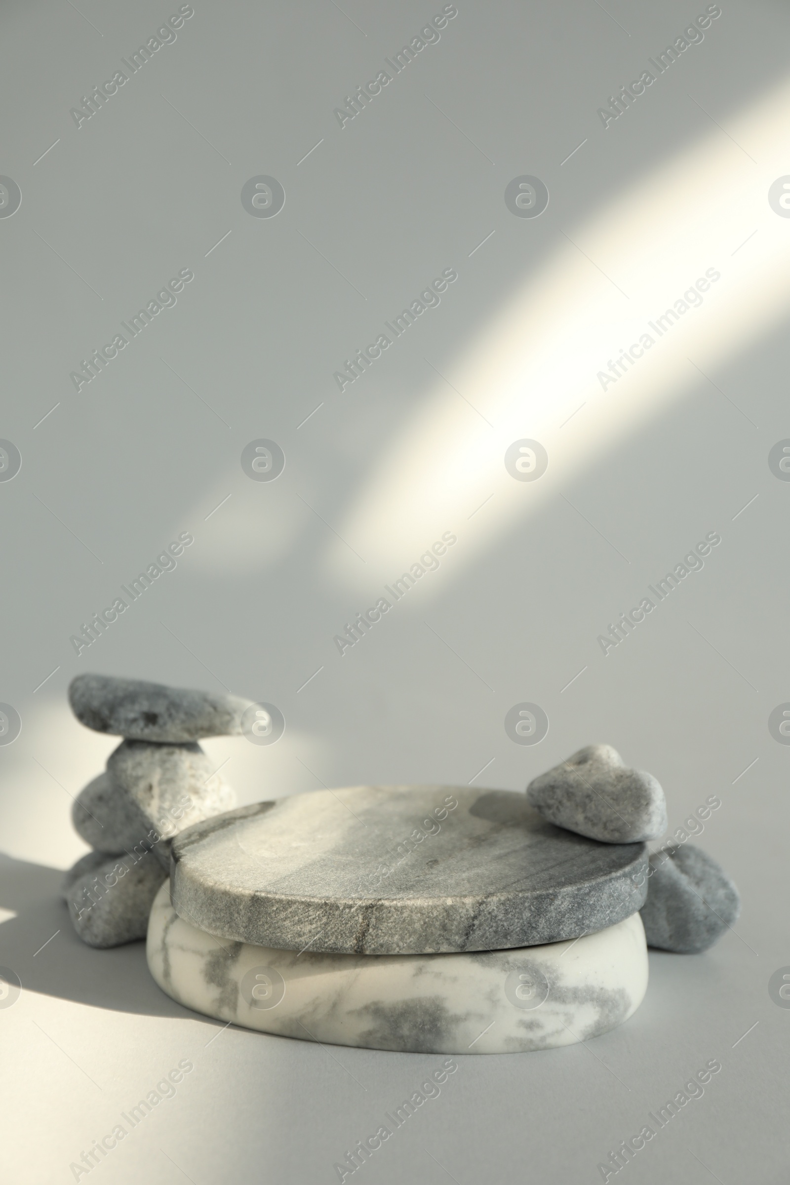 Photo of Presentation for product. Stone podium and pebbles on light grey background. Space for text