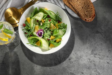 Photo of Delicious salad with cucumber and orange slices served on gray table, flat lay