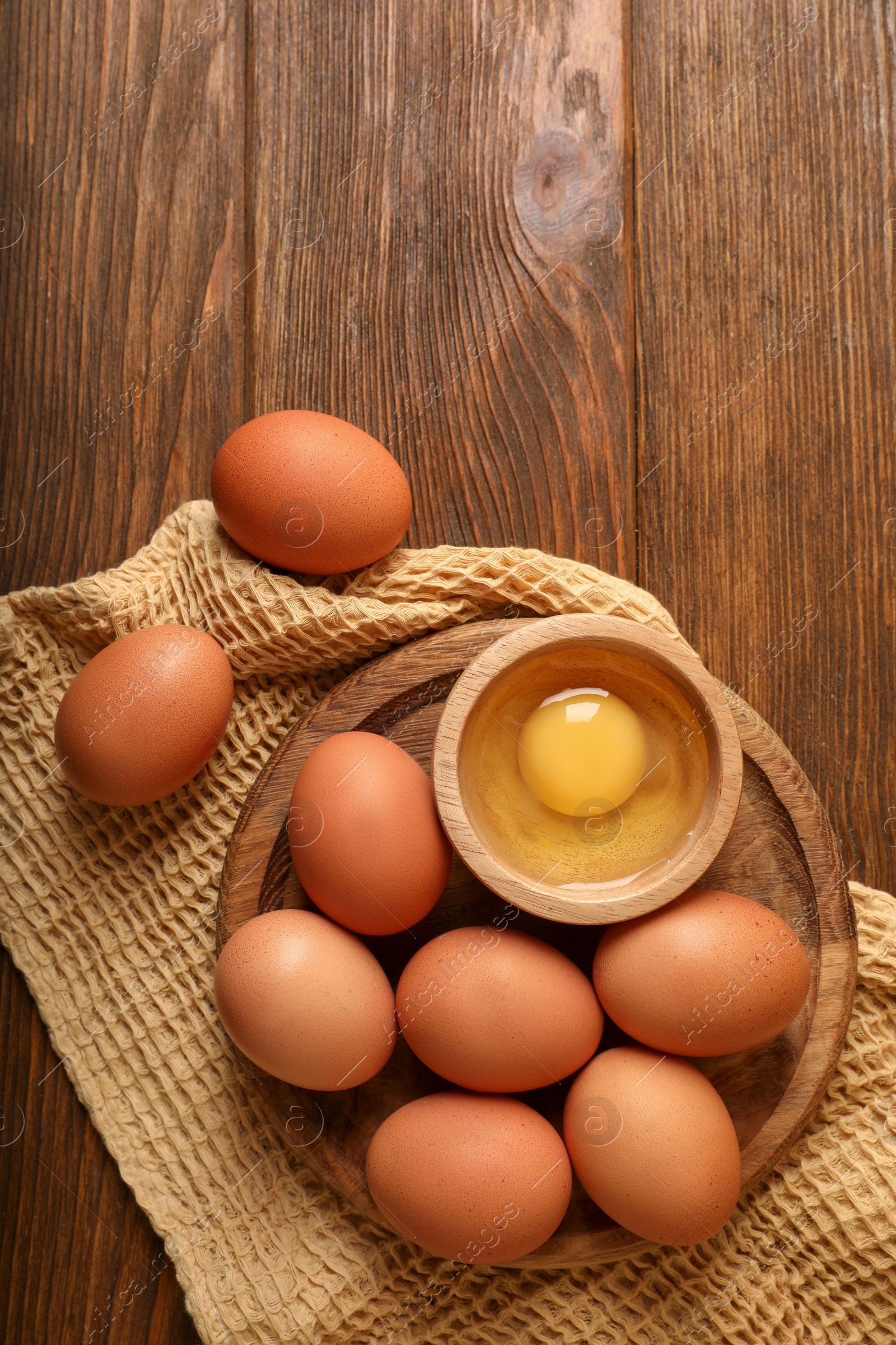 Photo of Raw chicken eggs on wooden table, flat lay. Space for text