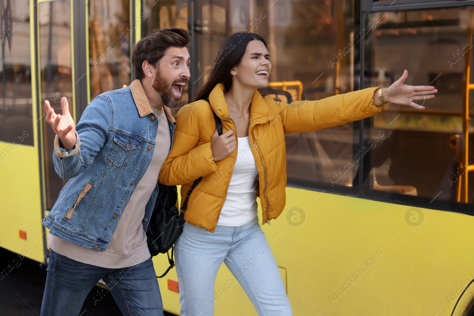 Photo of Being late. Worried couple running towards bus outdoors