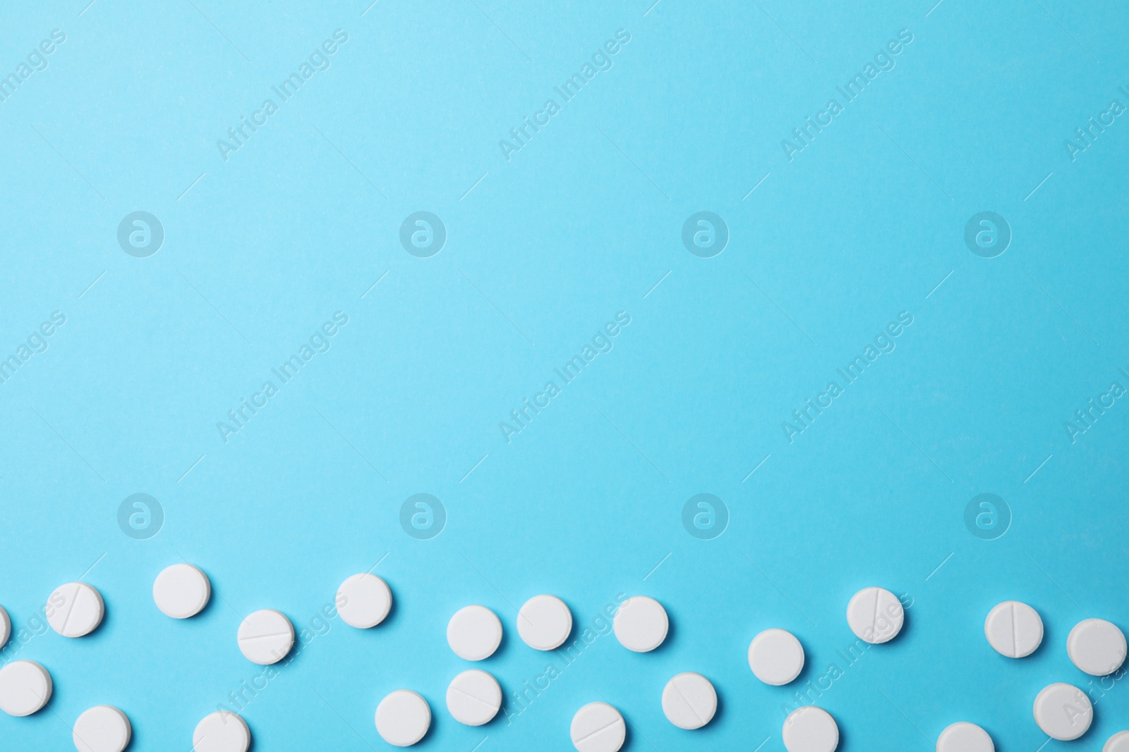 Photo of White pills on light blue background, flat lay. Space for text