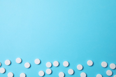 White pills on light blue background, flat lay. Space for text