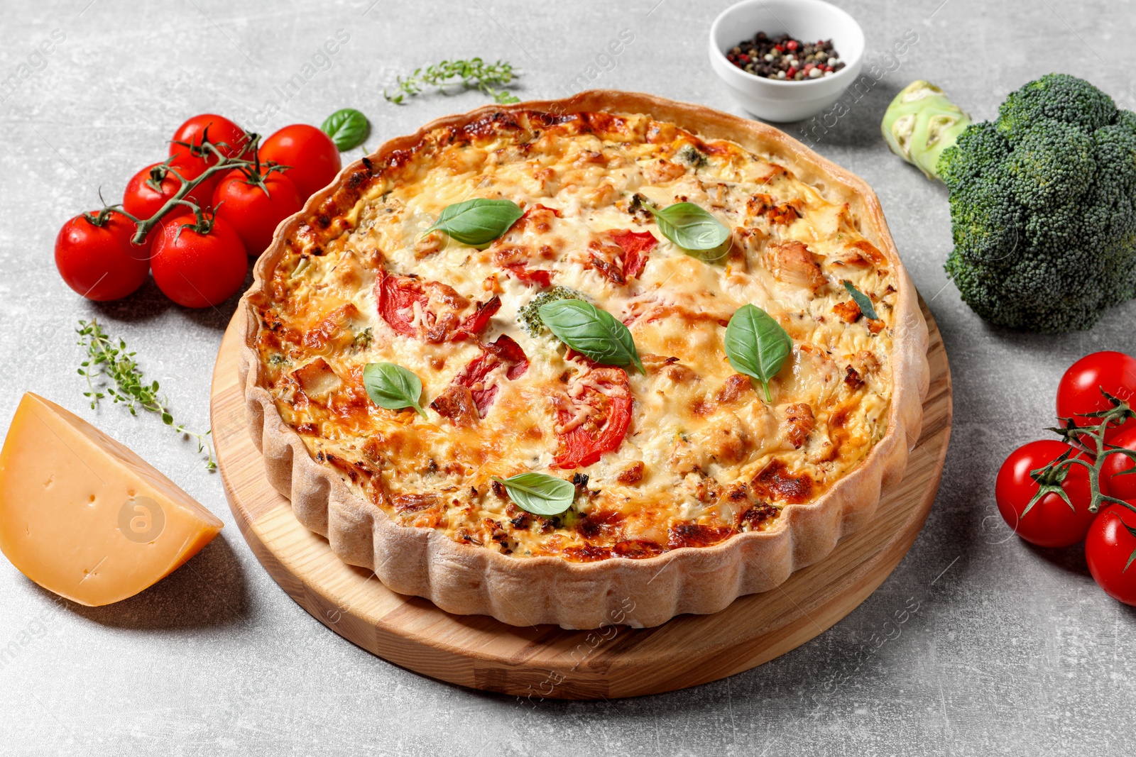 Photo of Tasty quiche with tomatoes, basil and cheese served on light table, closeup